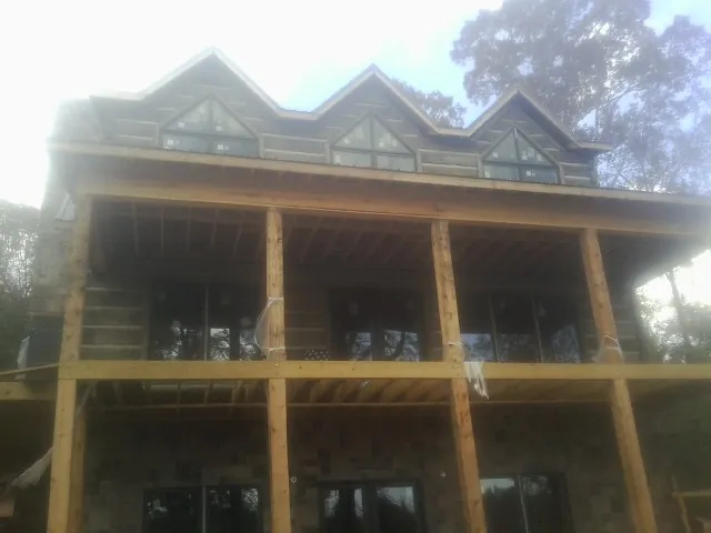 Dormers and porch framing on a large log home under construction — Roof Coating work by our crew in Cleburne